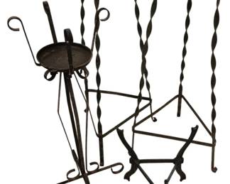 3751 - 4 Vtg Wrought Iron Plant Stands (Description): Set of four vintage wrought iron plant stands  featuring twisted metal legs and decorative  curled feet. The stands include two matching  taller pieces with circular ring tops  designed to hold planters, one stand with a round dish platform, and one lower triangular  base stand. Each piece displays handcrafted  ironwork with elegant spiral detailing.  Tallest measures 35 inches.