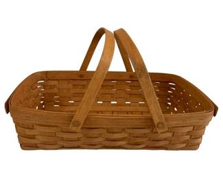 596 - Vintage Longaberger Basket 4.5"x18"x12" (Description): Woven splint basket featuring a rectangular  form with two swing handles attached at each  end. The basket displays traditional  craftsmanship with interlaced wood splints in  a natural honey-toned finish. Measures 4.5 inches tall by 18 inches long by 12 inches  deep.