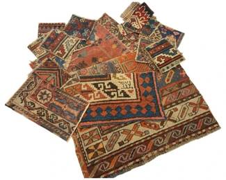 972 - Antique Caucasian Rug Fragments Collection (Description): A collection of antique Caucasian rug  fragments featuring traditional geometric  patterns and motifs. The fragments display  characteristic tribal designs including  diamonds, medallions, and stylized figures in rich earth tones of rust, blue, cream, and  tan. These textile remnants showcase the  intricate hand-knotted craftsmanship typical  of Caucasian weaving traditions.