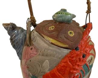 287 - Japanese Banko Ware Teapot 6"x6" (Description): Japanese Banko ware teapot featuring  elaborate relief decoration of sea life  including a lobster, various fish, and a  conch shell spout. The lid is formed as a  fish with a smaller fish finial. The teapot has a woven rattan bail handle.