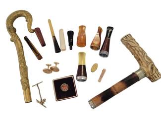 452 - 1955 Ford Pin & Other Men's Accessories (Description): A diverse collection of men's accessories  including a carved antler or bone cane handle  with horn shaft, an ornate brass cane handle  with serpent or fish motif, various cigar  and cigarette holders in horn, amber, and ivory tones with silver mounts, gold-filled  cufflinks, a tie clip, a corkscrew, and a  boxed pin or badge. The lot represents a  variety of gentleman's personal effects from  the late 19th to early 20th century.