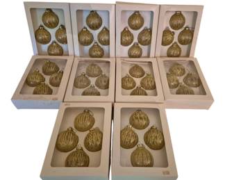 4072 - 10 Sets of 4 Gold Glass Christmas Ornaments (Description): Collection of 10 boxed sets of gold Christmas  ornaments, with 4 ornaments per set for a  total of 40 ornaments. Each ornament features  a ribbed glass design with gold glitter  finish and gold-tone metal caps with hanging loops. The ornaments are presented in their  original cream-colored display boxes with  clear windows.