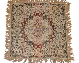 1435 - Fringed Table Scarf 36"x36" (Description): This square textile features an ornate  central medallion design with intricate  floral and bird motifs throughout. The piece  displays a color palette of cream, burgundy,  olive green, and dark blue in a Persian-inspired pattern. Bordered edges with  stylized floral vines frame the composition,  and all four sides are finished with  cream-colored knotted fringe.