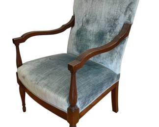1347 - Antique Chair w/ Blue Velvet Upholstery (Description): Antique armchair featuring blue velvet  upholstery with a gracefully arched back and  padded seat. The mahogany frame showcases  elegant carved details including reeded arms  with rosette terminals and tapered fluted front legs in a Federal or Sheraton style.  Measures 43.5" x 30" x 24.5".  Repair to arm