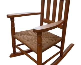 1335 - Vintage Child's Rocker w/ Rush Seat (Description): A charming child's rocking chair featuring a  traditional design with a woven rush seat.  The wooden frame includes slatted back  supports, turned finials, and shaped  armrests. Measures 22.5 x 21 x 15