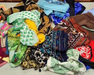 2852 - Lot of Assorted Colorful Fashion Scarves (Description): A diverse collection of assorted fashion  scarves in a wide variety of colors,  patterns, and fabrics. The lot includes solid  colors such as orange, pink, blue, and  brown, as well as an array of printed designs featuring polka dots, florals, paisleys, and  abstract motifs. Materials appear to include  silk, polyester, and other lightweight  fabrics suitable for various styling options.