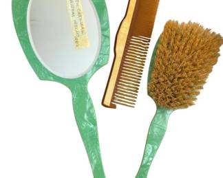 1366 - Celluloid Green Marbled Dresser Set (Description): Featuring a coordinating hand mirror and  hairbrush in green marbled celluloid,  accompanied by an amber-toned comb. The set  displays the characteristic swirled pattern  typical of mid-century vanity accessories.