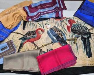 2859 - Lot of Designer Scarves (Description): A collection of named designer scarves  featuring various brands including Chaps,  Christian Dior, Perry Ellis, and Oscar de la  Renta. The lot includes an assortment of  patterns and colors including a decorative parrot motif scarf, striped designs in blue  and burgundy tones, solid colors in gold,  pink, and gray, as well as a floral pattern  on taupe. The scarves represent a variety of  styles suitable for different occasions.