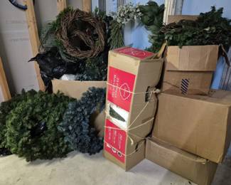4080 - Group of Christmas Tree, Wreaths & Garland (Description): A collection of Christmas decorations  including artificial Christmas trees in  various sizes with some still in original  boxes, decorative wreaths including a natural  grapevine wreath and several evergreen-style wreaths with holly accents, and assorted  holiday garland. The lot includes both green  and frosted blue-tipped artificial trees.  Some items remain boxed while others are  displayed.