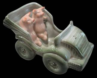 2820 - Vtg German Porcelain Pigs in Car Figurine (Description): Vintage German-style porcelain figurine  depicting two pink pigs riding in an antique  green automobile. The whimsical piece  features a celadon green glazed car with  detailed wheels and grille, with two charming pink pigs posed as passengers. This  decorative novelty piece showcases the  playful fairing style popular in early 20th  century German porcelain. Measures 3"x5"x3".