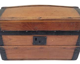 457 - Doll Trunk Domed Top 16.5"x10.5"x10" (Description): Antique doll trunk with domed top, featuring  pine wood construction with decorative  embossed metal corner brackets and banding.  The trunk has a central lock plate on the  front and metal strapping for reinforcement. Shows natural patina consistent with age.  Measures 16.5"x10.5"x10".