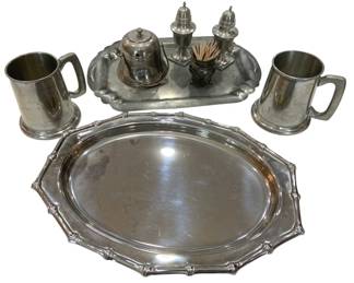948 - Silver Plated Tableware Collection (Description): A collection of silver plated tableware  including a large oval serving platter with  scalloped bamboo-style edge detailing, a  smaller rectangular tray with shaped rim  holding a condiment set with salt and pepper shakers, a lidded mustard pot, and a footed  toothpick holder. Also included are two  pewter tankard-style mugs with handles  featuring engraved inscriptions.