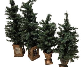 4083 - Group of 4 Medium Artificial Christmas Trees (Description): A group of four medium artificial Christmas  trees in decorative planters. The collection  includes trees of varying heights, each set  in ornate gold-toned bases featuring  scrollwork and urn-style designs. The trees feature realistic green needle foliage and  are suitable for holiday display.