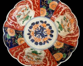 496 - Japanese Imari Bowl 3"x9.5" (Description): Japanese Imari porcelain bowl featuring  traditional hand-painted decoration in the  characteristic palette of iron red, cobalt  blue, and gilt. The scalloped rim frames  alternating panels depicting phoenixes amid flowering branches and chrysanthemum blossoms  on cobalt grounds. The central medallion  displays a floral arrangement of peonies in  blue and orange. The bowl exhibits the  classic Imari style popular during the Meiji