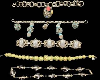 2808 - Collection of Five Vintage Costume Bracelets (Description): A collection of five vintage costume  bracelets featuring diverse styles. Included  is a twisted rope chain bracelet with a  decorative charm featuring colorful  cabochons, a charm bracelet with ornate filigree balls and turquoise-colored enamel  details, a link bracelet set with frosted  rectangular stones in decorative silver-tone  settings, a graduated bead necklace/bracelet  in mottled yellow-green tones, and a clear