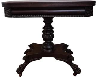 304 - Antique Mahogany Pedestal Game Table 29"x36" (Description): Antique mahogany pedestal game table  featuring a fold-over top that opens to 36  inches. The table showcases beautiful  Empire-style details including carved  acanthus leaf decoration on the turned pedestal column, gadrooned edge molding along  the apron