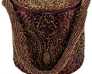 153 - Vintage Beaded Handbag Half Cylinder (Description): Vintage beaded handbag in a distinctive half  cylinder shape. The bag features intricate  beadwork in gold and bronze tones against a  burgundy fabric background, with decorative  beaded fringe detailing along the sides. Measures 6 inches by 6 inches by
