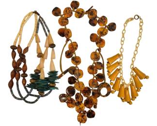 1483 - Group of Three Vintage Statement Necklaces (Description): A collection of three vintage statement  necklaces featuring diverse materials and  styles. The grouping includes a multi-strand  necklace with carved brown beads and  cream-colored bone elements with teal accents, a dramatic tortoiseshell-style disc  necklace with graduated circular pendants,  and a butterscotch-colored Bakelite-style  necklace with dangling tapered drops on a  chain link strand. Each piece exemplifies