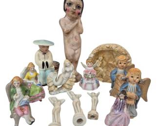 2711 - Group of Ceramic and Porcelain Figurines (Description): A diverse collection of ceramic and porcelain  figurines including angels, a vintage  chalkware-style figure of a young child,  ladies in period dress seated on a bench, a  sailor figure, small bud vases in figural forms, and decorative religious pieces. The  group features various styles ranging from  mid-century kitsch to traditional motifs,  with hand-painted details throughout.