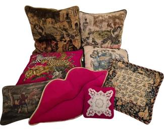 3916 - Group of Decorative Pillows (Description): A group of decorative throw pillows featuring  various designs and styles. The collection  includes tapestry-style pillows with scenic  imagery depicting figures in classical  settings, a vibrant fuchsia pink lip-shaped pillow, a needlepoint pillow with safari  animals including a lion, zebra, and cheetah  on a pink ground, a pillow with vintage  automobile motif, a sampler-style pillow with  alphabet letters and woodland creatures, and