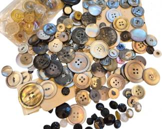 1456 - Assorted Vintage Buttons Collection (Description): A collection of assorted vintage buttons in  various sizes, styles, and materials. The lot  includes mother of pearl buttons in natural  iridescent tones, black glass buttons with  faceted designs, shell buttons in cream and gray hues, and plastic buttons in amber and  clear tones. Some buttons remain on their  original cards while others are loose or  stored in a small plastic container. An  excellent variety for sewing projects,