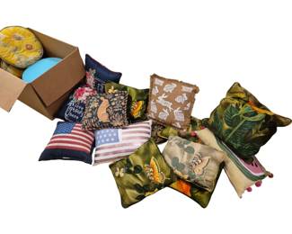 4015 - Group Lot of Decorative Throw Pillows (Description): Group lot of decorative throw pillows  featuring a variety of designs and themes.  The collection includes patriotic American  flag pillows, seasonal Easter bunny and  spring-themed pillows, nature-inspired designs with butterflies and tropical  foliage, floral patterns including a round  sunflower pillow, and whimsical designs  including a watermelon pillow with pom-pom  trim. Various sizes and shapes represented in