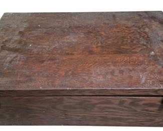 4104 - Wooden Box Full of Sewing Supplies (Description): A wooden box full of sewing supplies. The box  features a hinged lid with brass-tone  latches on the front for secure closure. The  wood shows a warm brown finish with natural  grain visible, displaying signs of age and use consistent with a well-used sewing box.