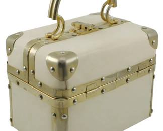 1775 - Delill Trunk Handbag Cream 10"x8"x5" (Description): Delill trunk handbag in cream. This  structured box-style purse features a  distinctive trunk silhouette with metal  hardware accents. Measures 10 inches by 8  inches by 5 inches.