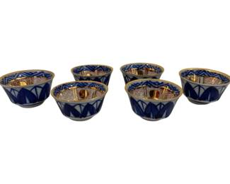 321 - Blue & White Porcelain Sake Cups w/ Gold (Description): Chinese porcelain bowl decorated in the  Famille Rose palette featuring hand-painted  figural scenes depicting a woman in  traditional dress on a terrace with pagodas,  willow trees, and architectural elements. The interior rim is adorned with colorful floral  motifs, scrollwork, and geometric patterns.  The bowl shows typical characteristics of  Chinese export porcelain with polychrome  enamels on a white ground. Measures 4.5" x