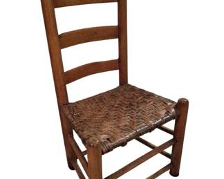 3745 - Primitive Ladder Back Chair w/ Woven Seat (Description): Primitive ladder back chair featuring a woven  splint seat in a herringbone pattern. The  chair has a traditional three-slat ladder  back design with turned ball finials atop the  back posts. Constructed of solid wood with a warm, aged patina, the chair includes turned  front legs and stretchers for stability.  Measures 36 inches high x 19 inches wide x  13.5 inches deep.