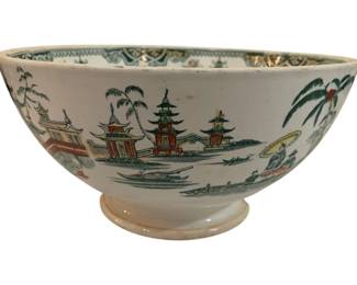299 - Japanese Chinoiserie Footed Bowl 5"x9" (Description): Japanese footed bowl featuring a chinoiserie  design with polychrome decoration depicting  pagodas, palm trees, figures with parasols,  and boats on water. The bowl has a  cream-colored ground with green, rust, and gold accents, and a decorative border along  the interior rim. There is a chip in the  base. Measures 5 inches tall by 9 inches in  diameter.