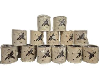 4028 - 18 Ceramic Dragonfly Candle Holders (Description): A collection of 18 ceramic candle holders  featuring dragonfly motifs. Each cylindrical  holder displays an applied dragonfly design  and decorative perforations throughout the  body. The holders have a rustic cream or tan finish with darker contrasting dragonfly  accents.
