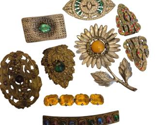 1482 - Vtg Rhinestone & Glass Brooches and Barrettes (Description): Collection of vintage brooches and barrettes  featuring rhinestone and glass  embellishments. The assortment includes a  silver-tone sunflower brooch with  amber-colored center, an eye-shaped brooch with green and clear rhinestones, a  rectangular modernist brooch with green glass  stone, ornate brass-tone brooches with  purple and pink stones, dress clips with  multicolored rhinestones in Art Deco style,