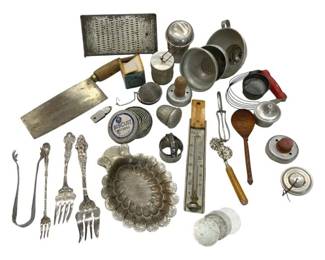 1250 - Vtg Kitchenware Collection Assorted Utensils (Description): A vintage kitchenware collection featuring an  assortment of utilitarian items. The lot  includes ornate silver-plated cocktail forks  with decorative handles, a claw-style sugar  tong, a scalloped decorative dish, a meat cleaver with wooden handle, a flat metal  grater, various tea strainers and infusers, a  folding ruler thermometer, a pastry wheel  with wooden handle, a wooden spoon, a wire  mesh strainer, aluminum measuring cups, a
