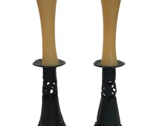 967 - Pr Cast Iron Pierced Candlesticks w/ Candles (Description): A pair of cast iron candlesticks featuring  pierced scrollwork design on the tapered  bases. The candlesticks have a dark finish  and include cream-colored taper candles with  flared tops. The openwork pattern creates a decorative silhouette.