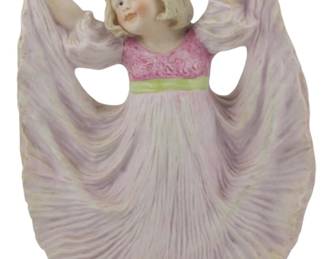 867 - Gebruder Heubach Bisque Figure Dancing Girl (Description): Gebruder Heubach bisque figurine depicting a  young girl in a dancing pose with arms  raised, holding the flowing skirt of her  lavender gown. She wears a pink bodice with a  green sash at the waist. The figure has blonde hair and a cheerful  expression.Measures 10 inches tall.