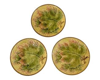 419 - 3 Majolica Leaf Plates 8" (Description): Three majolica plates featuring a large  decorative leaf design in green and pink  tones against a yellow textured background.  Each plate has a brown rim border. Measures 8  inches in diameter.