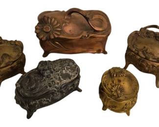 3925 - Group of 5 Art Nouveau Style Dresser Boxes (Description): A collection of five vintage Art Nouveau  style dresser boxes in various sizes and  finishes. The group includes boxes in copper,  brass, and silvered tones, each featuring  ornate embossed floral and scrollwork designs typical of the Art Nouveau period. Several  boxes are footed and feature hinged lids with  decorative handles. The largest box displays  a prominent daisy motif. All boxes show  characteristic romantic styling with organic