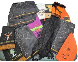 1437 - Halloween Themed Fringed Table Scarf & Decor (Description): A collection of Halloween-themed table linens  and accessories featuring a fringed table  scarf. The assortment includes pieces  decorated with spiderweb patterns in gray and  white, orange and black color schemes, and festive Halloween motifs. Various textile  items are included such as table runners and  decorative scarves with rickrack trim and  lace details, perfect for seasonal holiday  decorating.