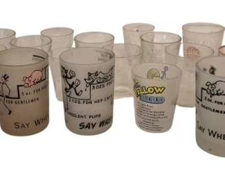 3968 - Collection of 27 Vtg Novelty Shot Glasses (Description): Collection of 27 shot glasses featuring  various novelty designs. The assortment  includes frosted and clear glass examples  with humorous illustrations, cartoon  characters, and whimsical sayings. Many feature mid-century style graphics with  phrases like "Say When" and colorful printed  decorations. A playful vintage barware  collection suitable for display or  entertaining.