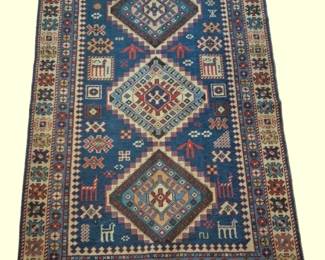 2796 - Vtg Caucasian Style Wool Rug 70"x43" (Description): Vintage Caucasian style wool rug featuring a  classic triple medallion design on a rich  blue field. The rug displays traditional  geometric motifs including stylized animals,  architectural elements, and symbolic patterns throughout the central field..Multiple  decorative borders frame the piece, with an  ivory outer border containing colorful  geometric repeating patterns. The rug retains  its original fringe at both ends. Measures