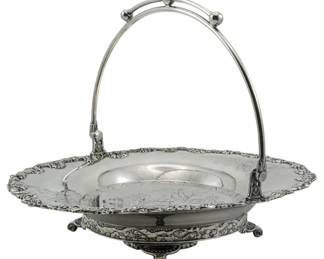 93 - Adelphi Silver Co. Quadruple Plate Basket (Description): Adelphi Silver Co. quadruple plate basket  featuring an ornate floral repousse border,  engraved decorative panels on the interior, a  swing handle with ball finials, and ball  feet. Measures 9 inches by 11 inches by 9 inches.