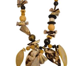1495 - Tribal Style Mixed Media Statement Necklace (Description): A bold tribal style statement necklace  featuring an eclectic mix of materials  including carved horn or shell pieces, wooden  beads in black, gold, and natural tones, and  decorative leaf-shaped pendants. The necklace showcases a variety of textures and  earthy colors with curved horn segments,  spherical beads, and elongated carved  elements arranged asymmetrically. The  centerpiece features a cluster of leaf