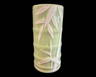545 - Japanese Celadon Porcelain Bamboo Vase (Description): A celadon green ceramic vase featuring a  molded bamboo stalk design with raised white  bamboo leaves cascading down the cylindrical  form. The vase has a glossy glaze finish and  measures 6 inches in diameter by 12.5 inches tall.