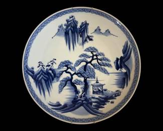 552 - Oriental Blue & White Porcelain Charger 16" (Description): Oriental blue and white porcelain charger  featuring a traditional hand-painted  landscape scene. The central design depicts a  mountainous setting with pine trees, pagoda,  and rocky outcroppings in classic Asian style. The rim is decorated with a continuous  wave or cloud pattern border. Measures 16  inches in diameter.