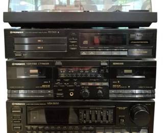 3994 - Pioneer Stereo Equipment Stack 4 Components (Description): Pioneer stereo equipment stack consisting of  four components. The system includes a  Pioneer VSX-3300 audio/video stereo receiver  at the base, a Pioneer CT-W600R dual cassette  deck, a Pioneer PD-T303 multi-tray CD player, and a turntable with dust cover on  top. All components feature black finish with  coordinating design aesthetic typical of  late 1980s to early 1990s home audio  equipment.
