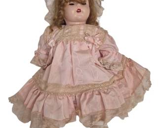 1265 - Vtg Composition Doll w/ Sleep Eyes Pink Dress (Description): Vintage composition doll featuring sleep eyes  and strawberry blonde curly hair. She is  dressed in a pink moire taffeta dress with  lace trim and ribbon accents, complemented by  a matching lace bonnet and soft shoes. The doll measures 22 inches in length.