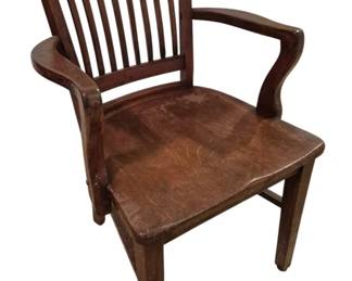 3746 - Oak Office Chair 35"x19"x20" (Description): Vintage oak office chair featuring a classic  banker's style design with vertical slat back  and curved armrests. The chair has a  contoured saddle seat and sturdy four-leg  base with stretchers for stability. Shows warm patina and wear consistent with age and  use.