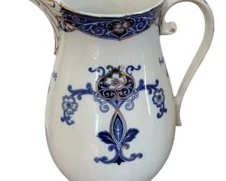 1345 - Vintage Blue & White Ironstone Pitcher (Description): Vintage blue and white ironstone pitcher  featuring decorative floral and scrollwork  motifs. The piece displays a classic  Victorian-era style with a cobalt blue band  around the rim accented with medallion designs, and coordinating floral patterns on  the body. The pitcher has a graceful curved  handle and gilt trim details. Measures 12".