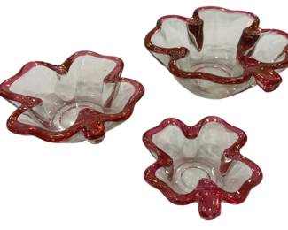 961 - 3 Glass Bowls w/ Cranberry Ruffled Rims (Description): Set of three clear glass bowls featuring  decorative cranberry-colored ruffled rims.  Each bowl has a flower-like shape with  scalloped edges and a pedestal foot in  matching cranberry glass. The graduated sizes make this an attractive nesting set.  Measures 3.5" x 8".